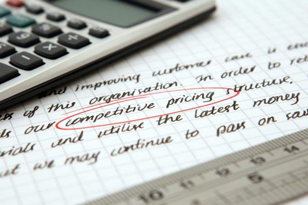 Close-up of a handwritten note highlighting 'competitive pricing structure' with a calculator and ruler, representing business strategy and financial planning.