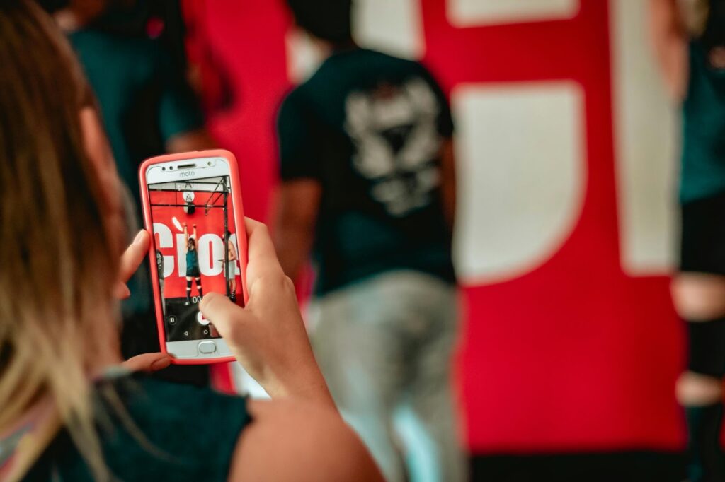 Person capturing a live event on a smartphone, emphasizing digital engagement and real-time sharing at a public gathering.